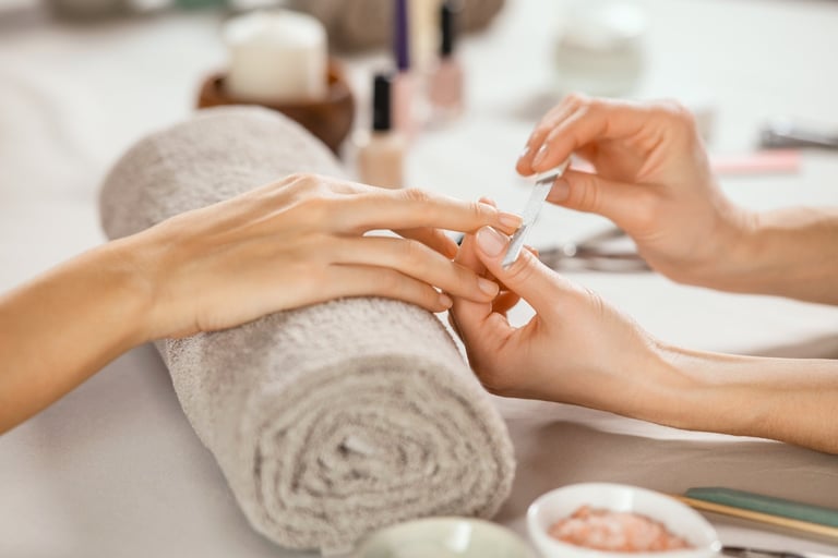 Close up of woman receiving manicure by beautician with metal nail file