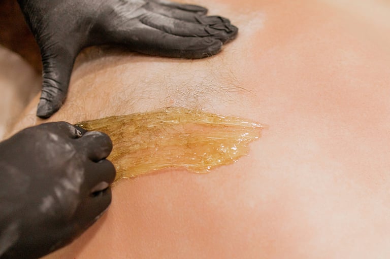 Beautician epilating male back with sugaring at beauty salon