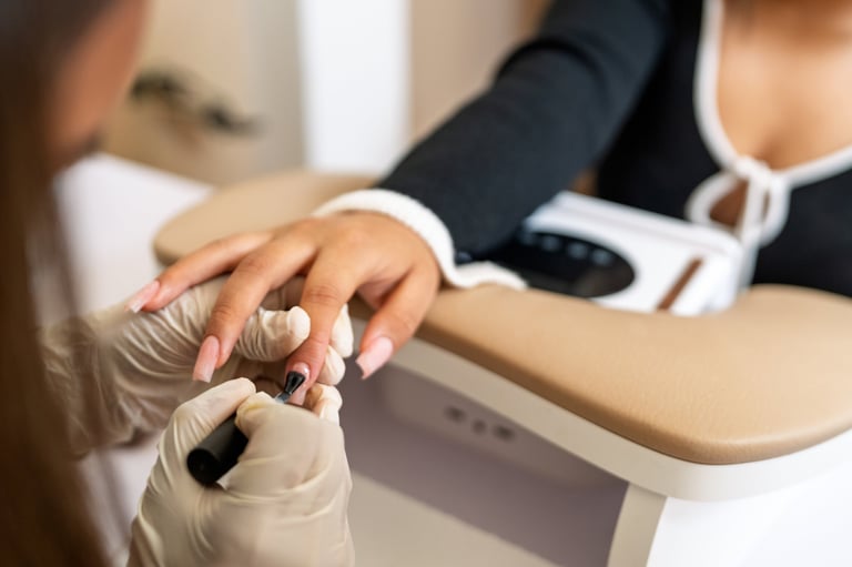 Manicurist applying nail polish to client hand with gel color