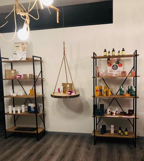 Retail beauty store display with tiered shelving and hanging organizer showcasing skincare and cosmetic products