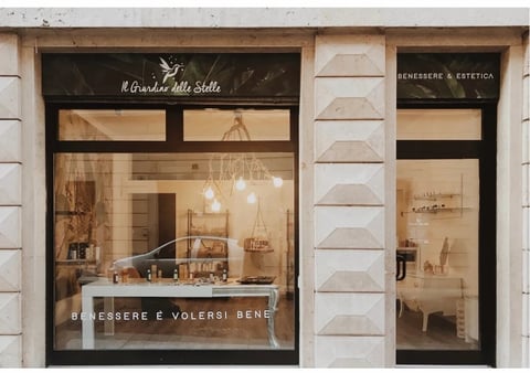 Storefront window of an Italian jewelry or accessories shop with elegant display featuring pendant lights and minimalist white decor